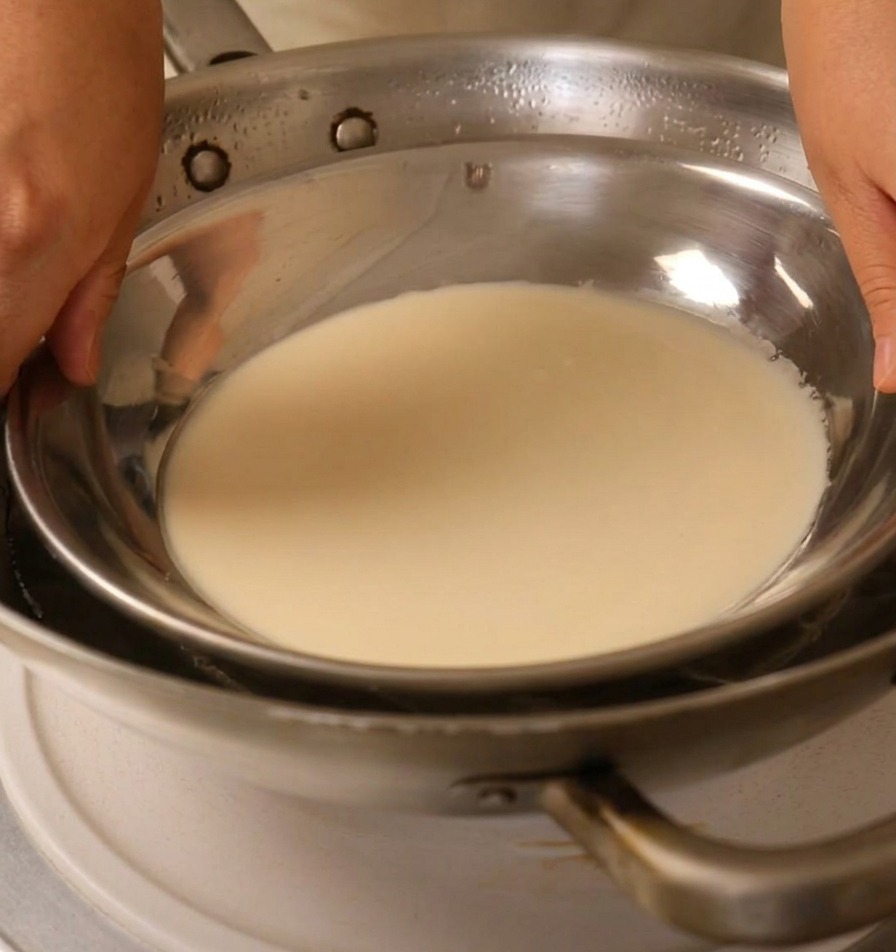 Plaque en métal avec la pâte placée sur un wok deau bouillante.