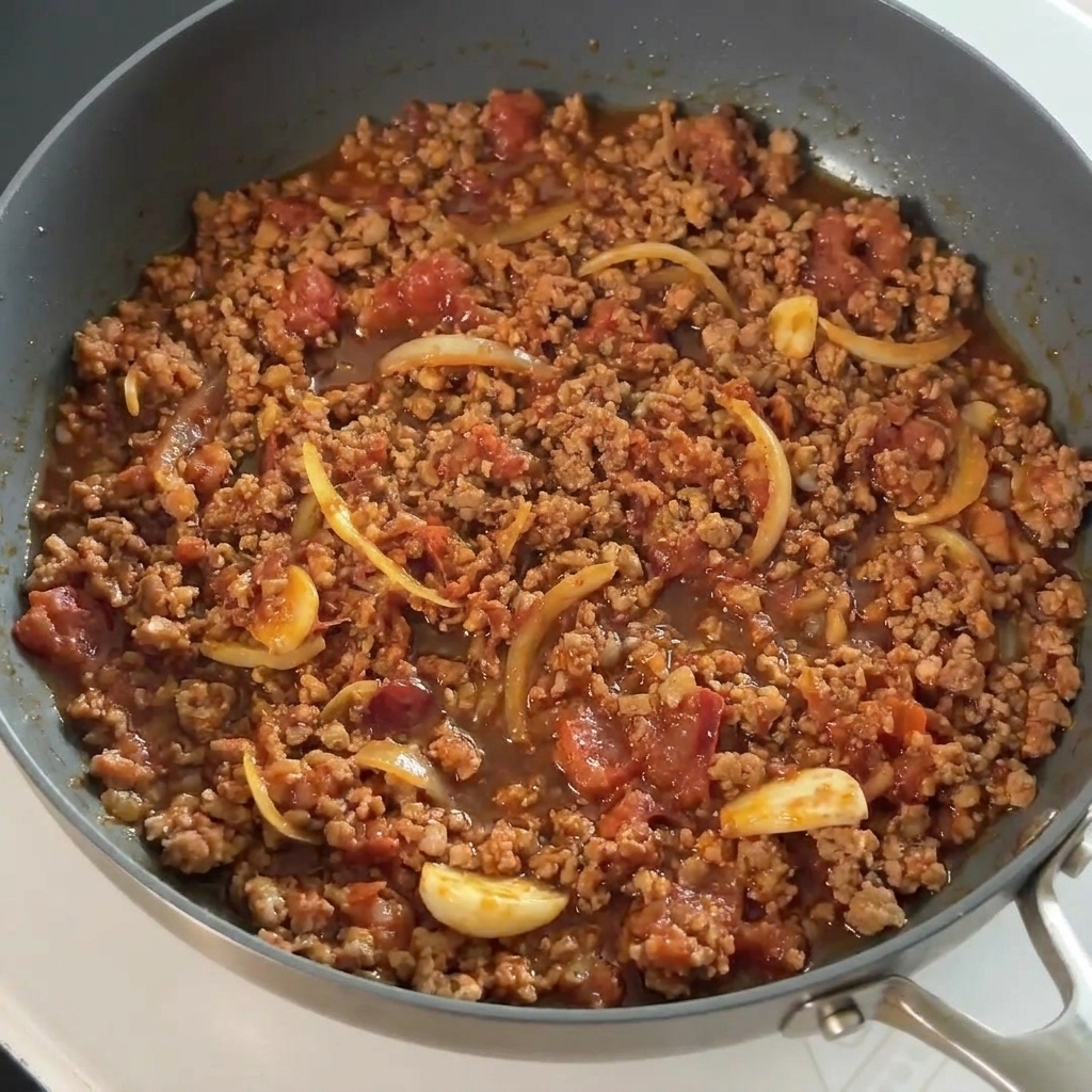 Sauce soja versée sur le mélange de porc dans la poêle.