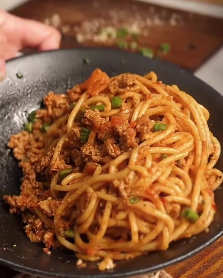 Spaghettis ajoutés dans la poêle avec la sauce.
