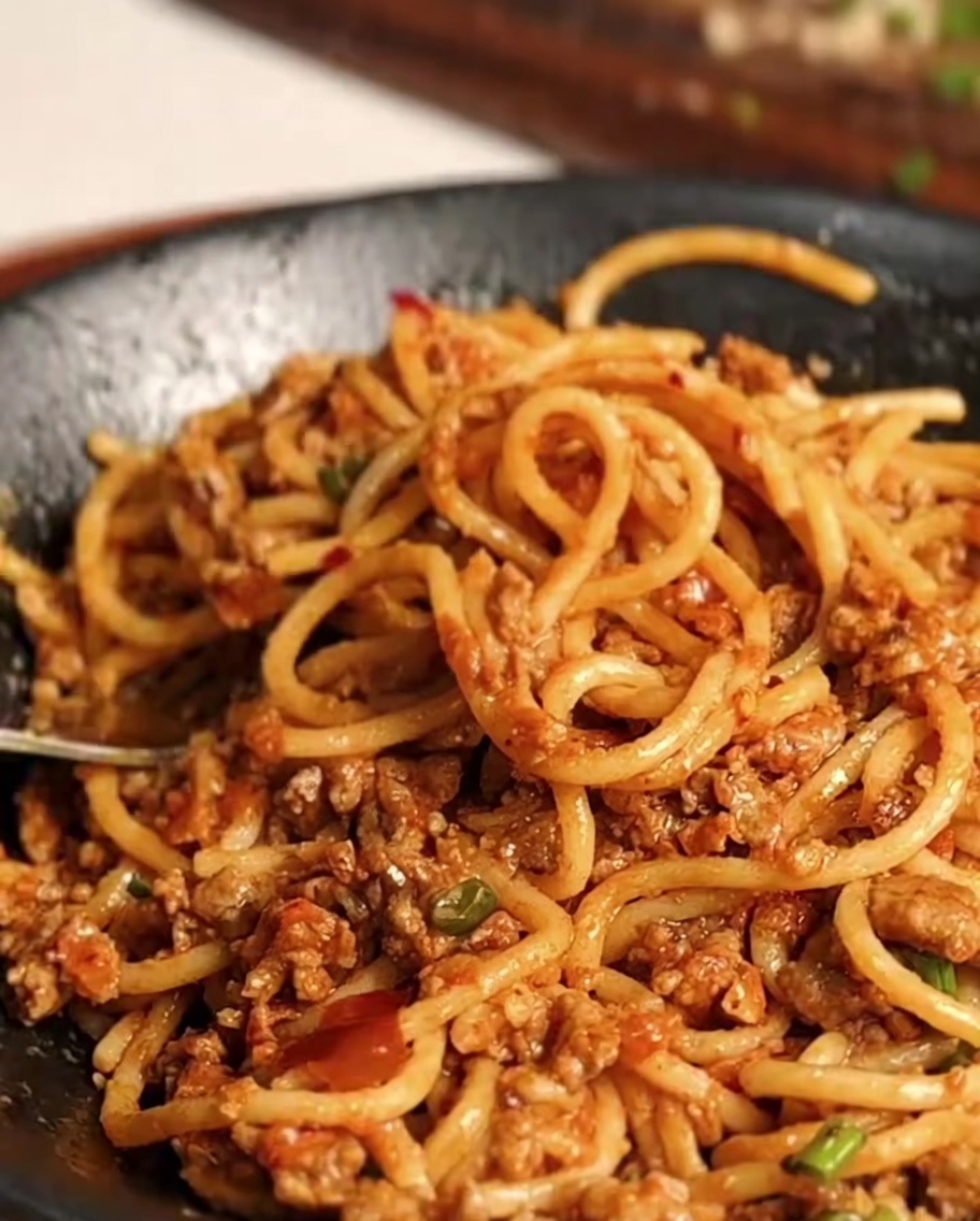 Spaghettis enrobés de sauce prêts à être servis.