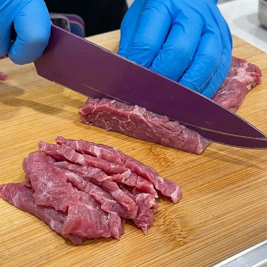 Gros plan sur du bœuf à braiser coupé en tranches fines sur une planche à découper en bois.