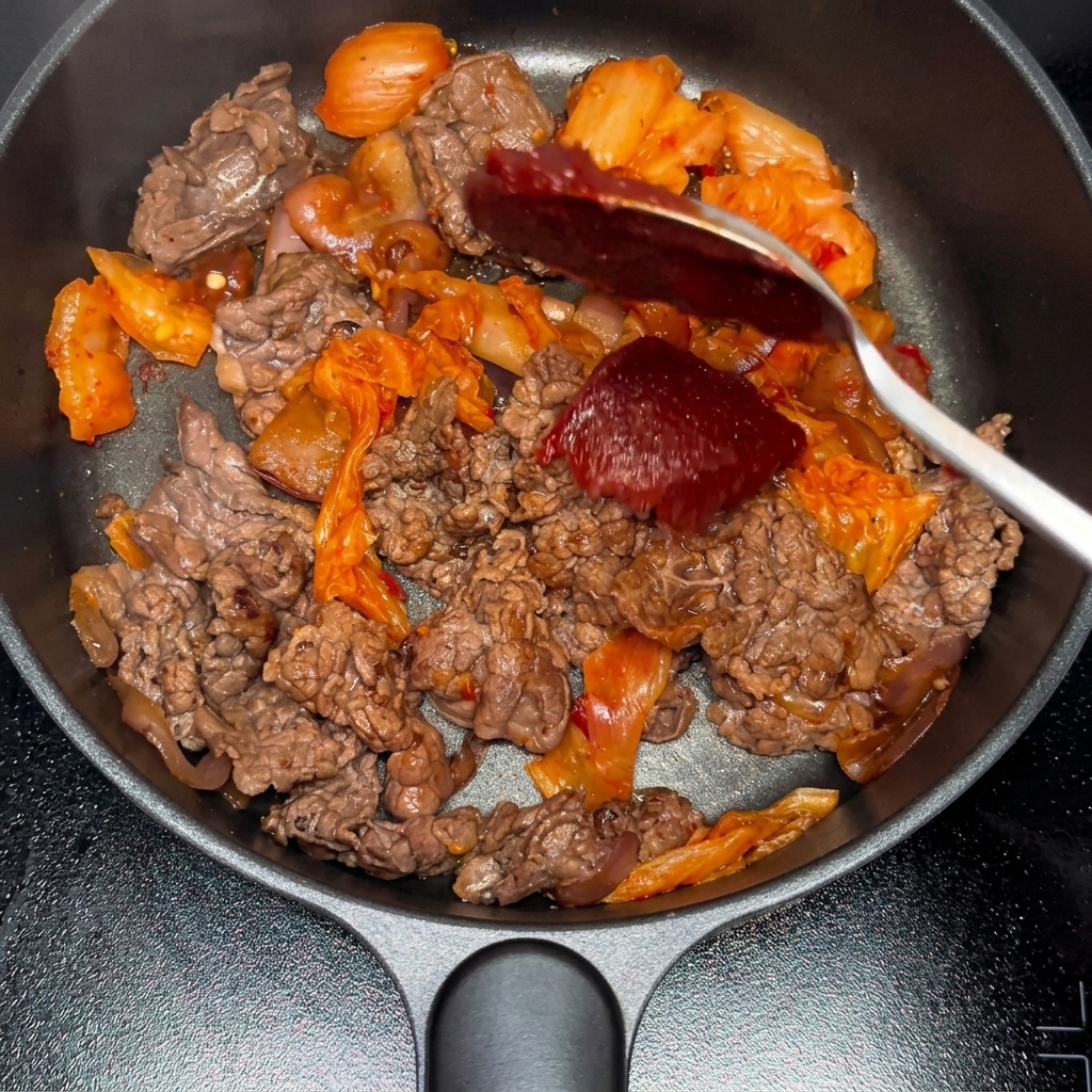 Pâte de piment et poudre de piment ajoutées au mélange bœuf-kimchi.