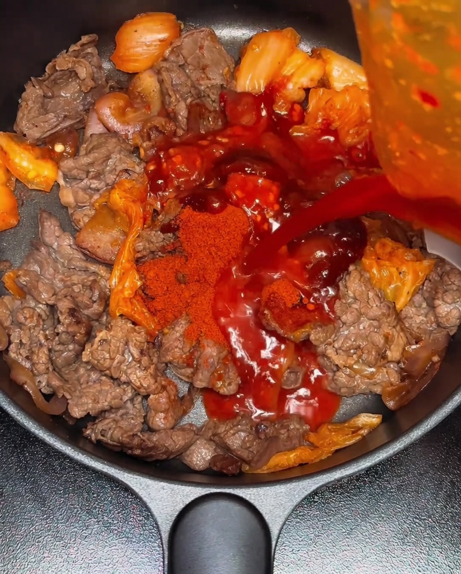 Eau versée dans la poêle contenant le mélange de bœuf et kimchi.