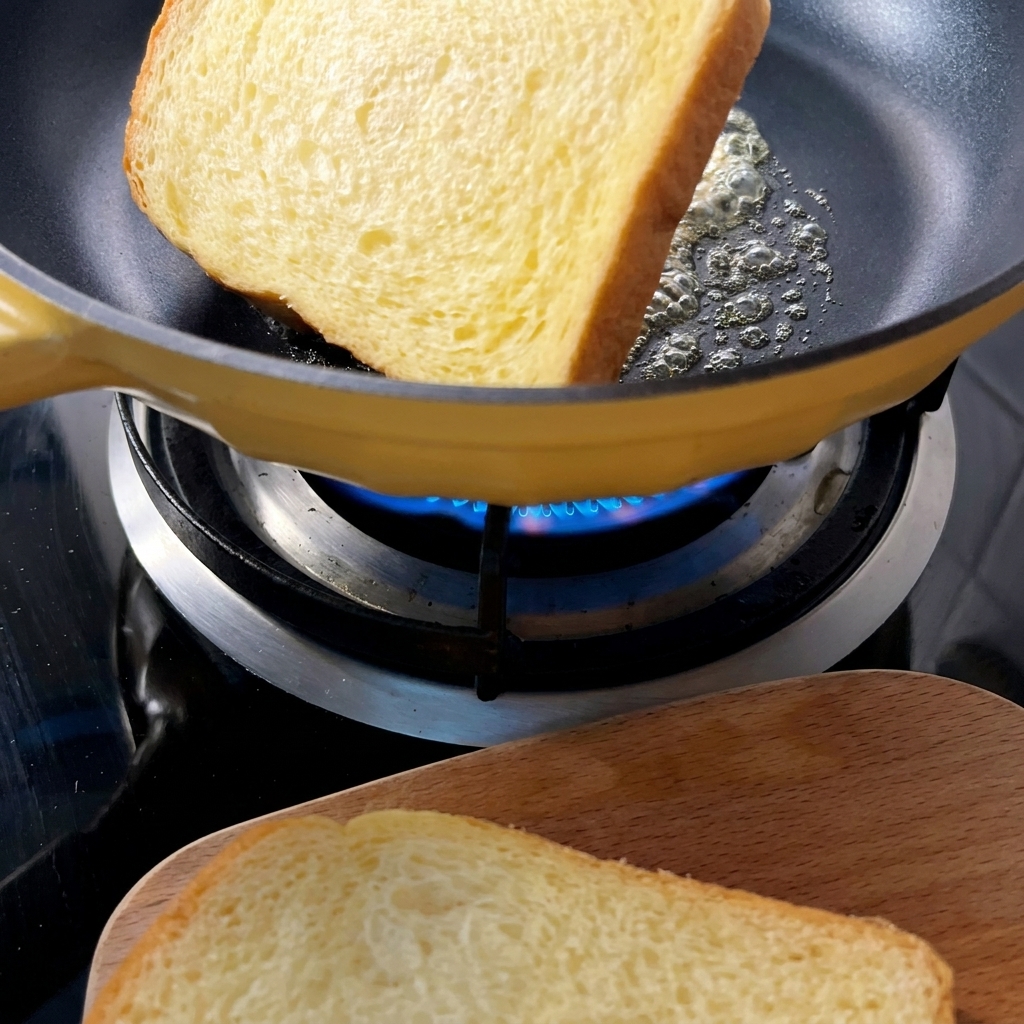 Tranches de pain dorées et toastées dans une poêle jaune avec du beurre fondu.