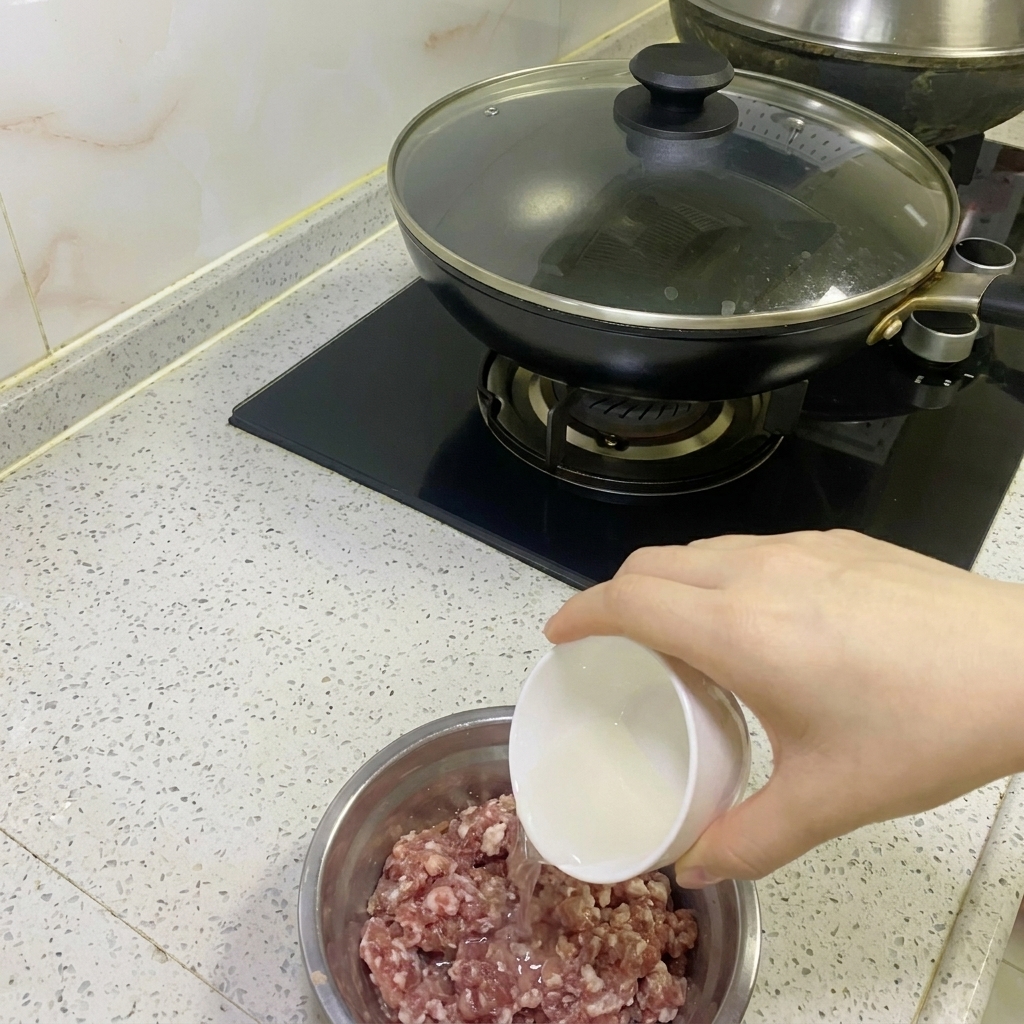 Eau doignon et gingembre versée dans un bol de viande hachée crue.