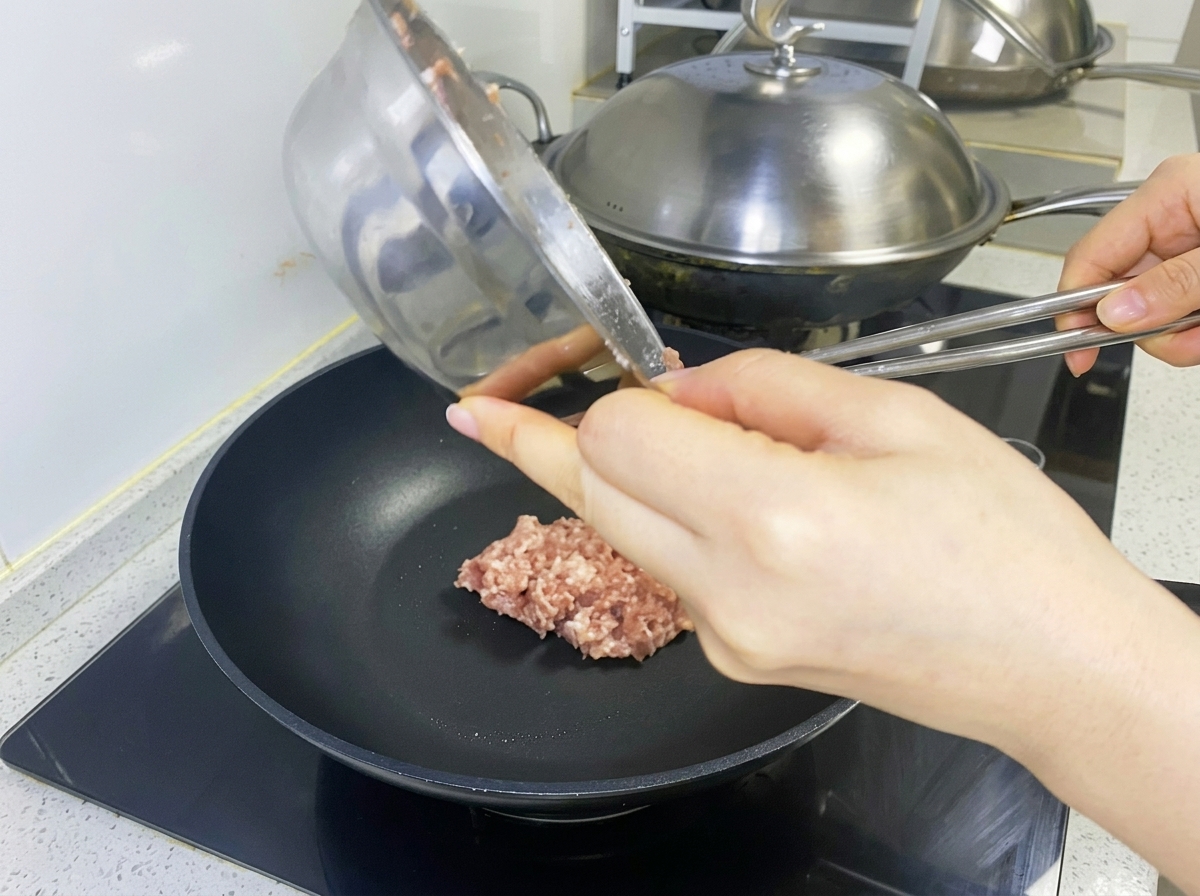 Mélange de viande crue placé dans une poêle noire pour former une galette.