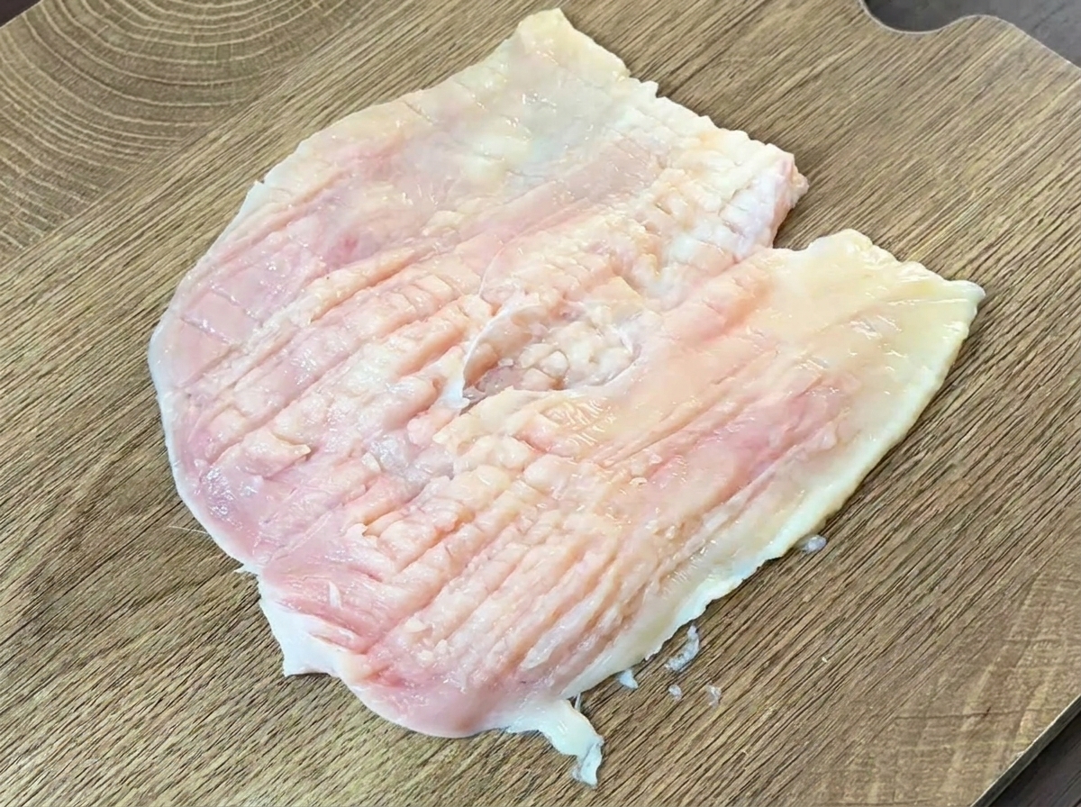 Le dos dun couteau lourd utilisé pour marteler et aplatir un blanc de poulet cru ouvert en portefeuille.