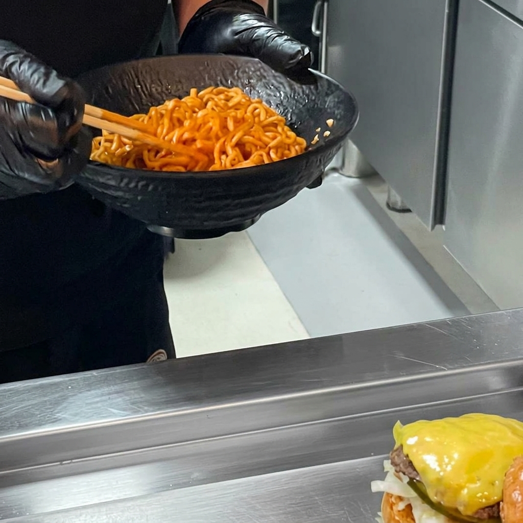 Un burger ramen au poulet épicé terminé par lajout dune montagne de nouilles ramen épicées sur le steak.