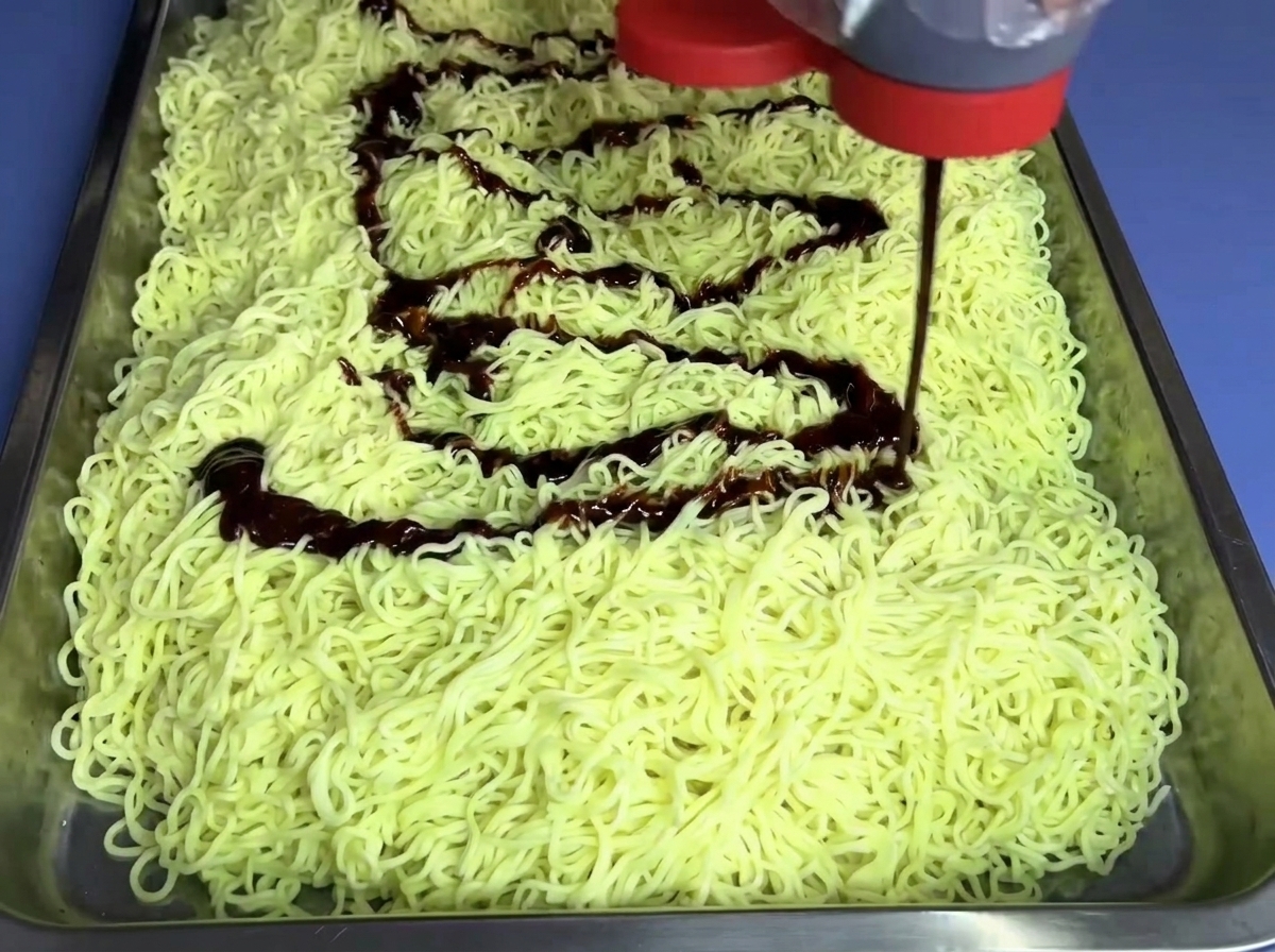 Sauce façon feu non épicée versée en filet sur un lit de nouilles.