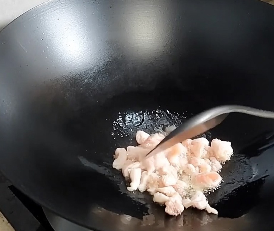 Dés de poitrine de porc brunissant et libérant leur gras dans un wok chaud.