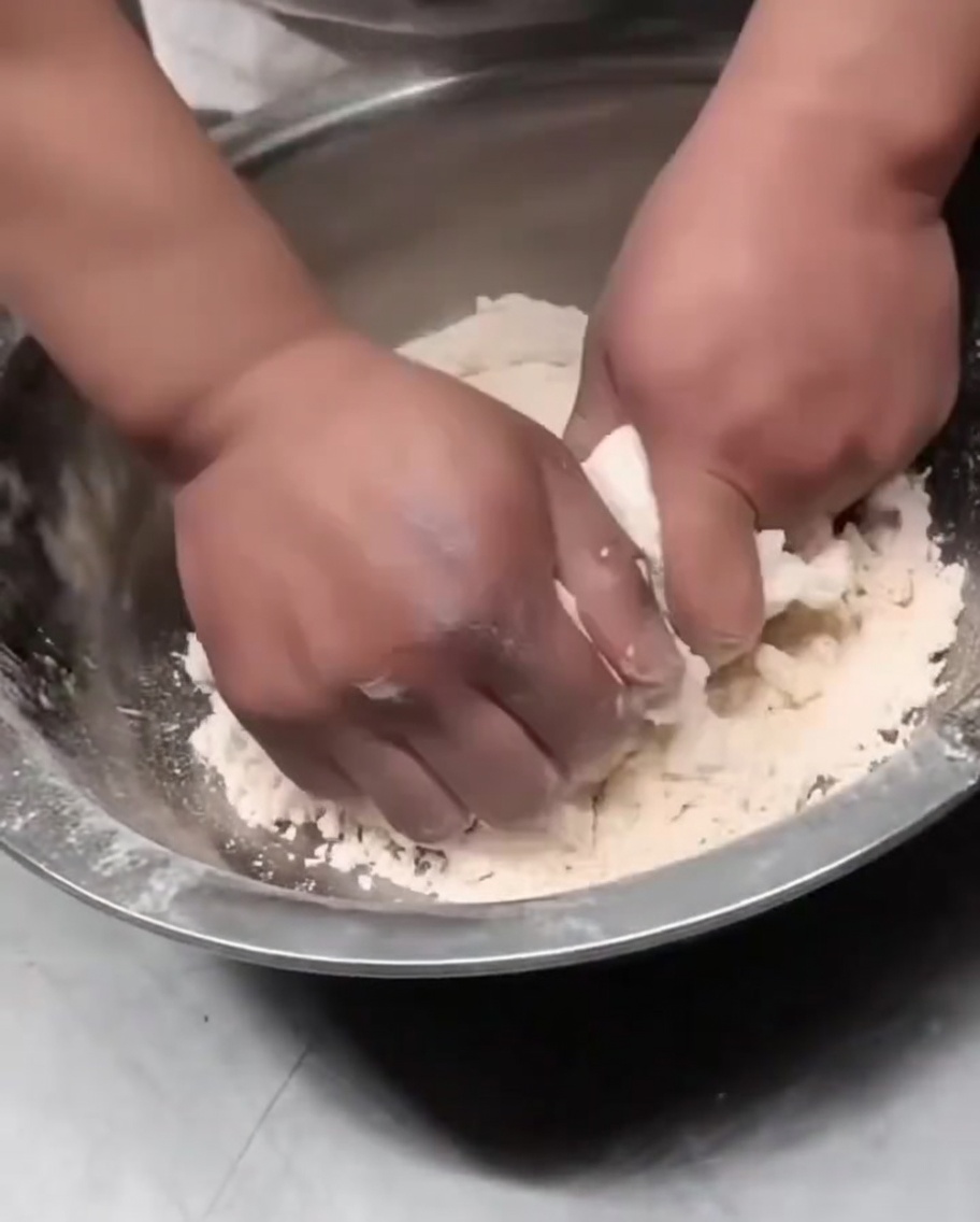 Mains pressant les flocons de pâte ensemble pour former une boule.