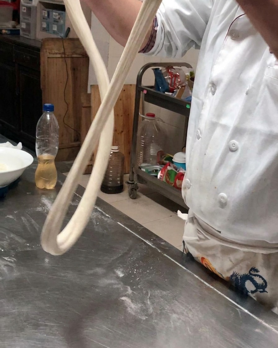 Un long boudin de pâte suspendu dans lair pour sétirer sous son propre poids.