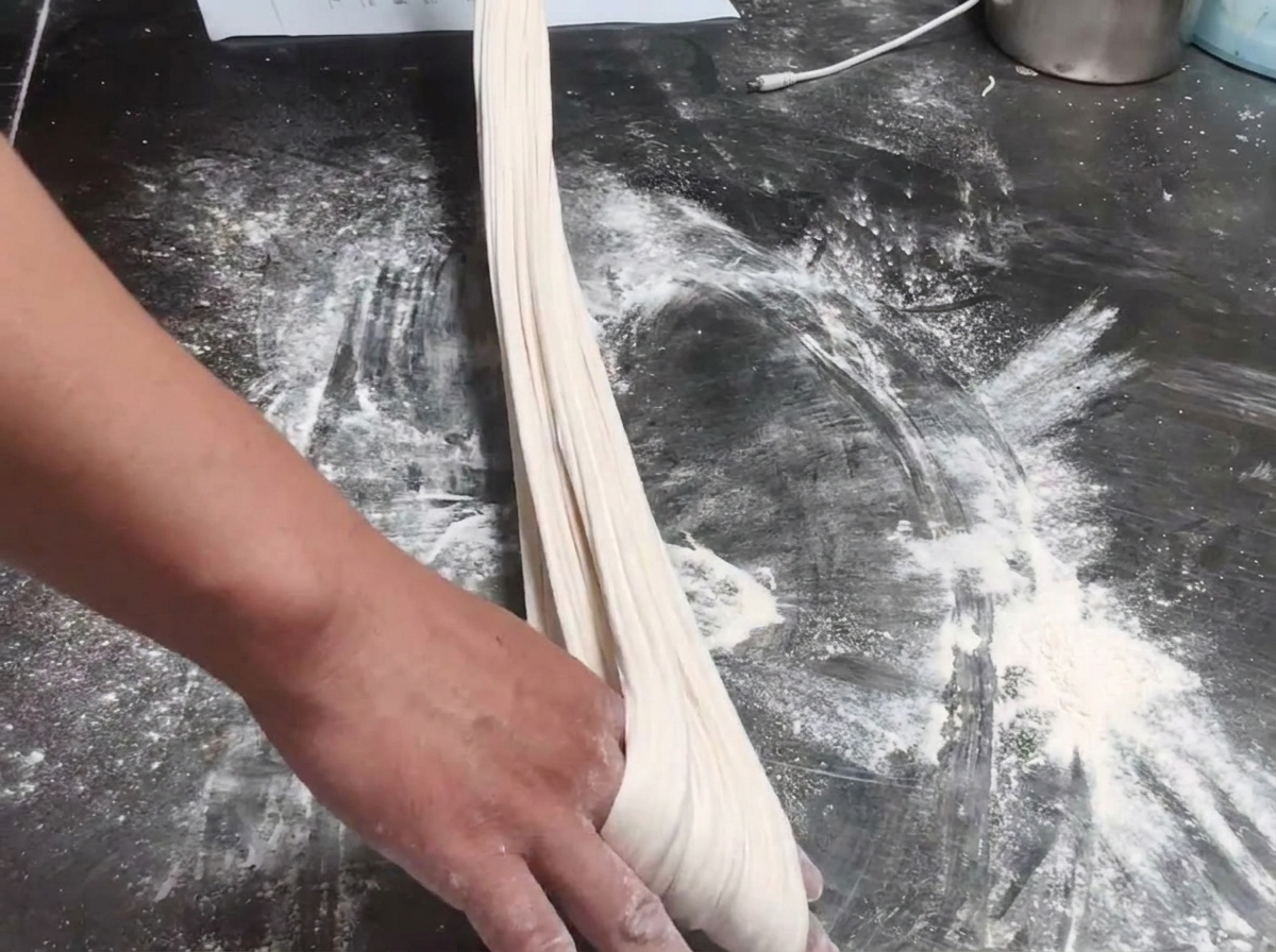 Boudin de pâte étiré et vérifié sur une table farinée.