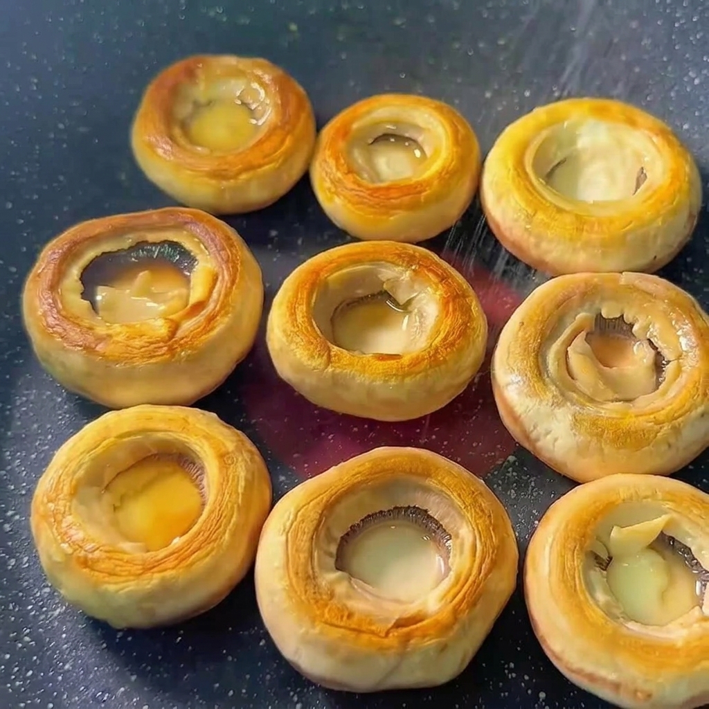 Chapeaux de champignons dans une poêle assaisonnés avec du sel et du poivre.