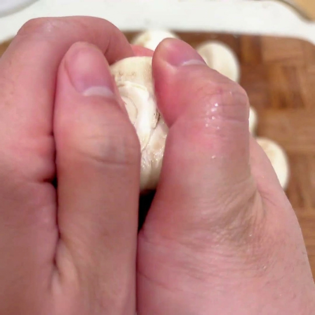 Gros plan sur des mains retirant le pied dun champignon de Paris pour préparer le chapeau à être farci.