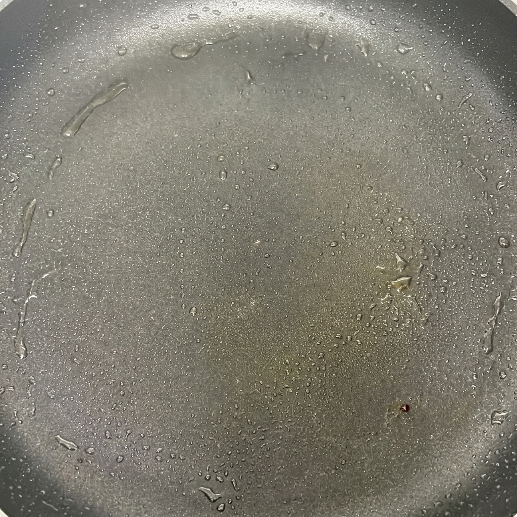 Chapeaux de champignons qui grésillent dans une poêle chaude avec de lhuile, commençant à dorer légèrement.