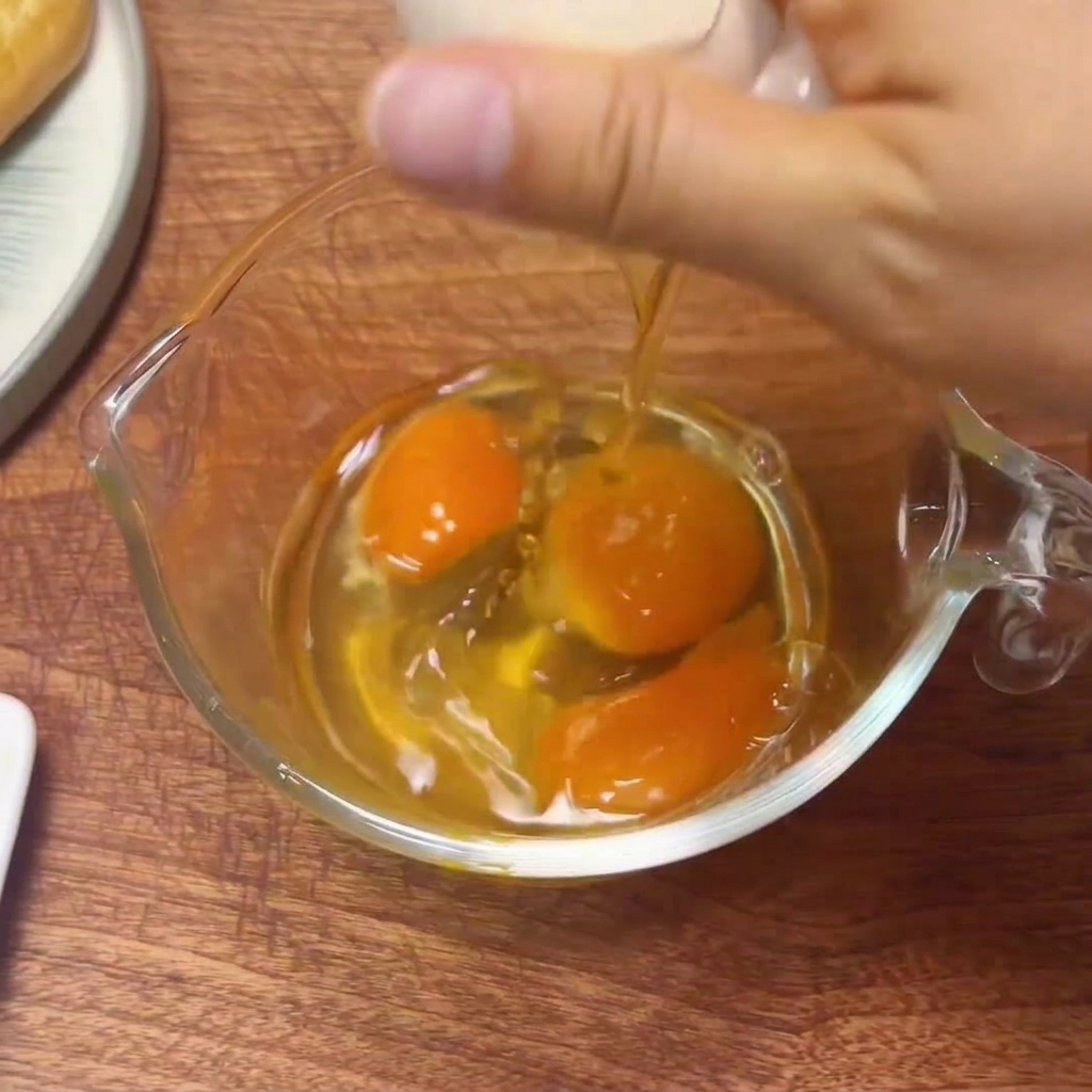 Œufs frais cassés dans un verre doseur, prêts à être battus.