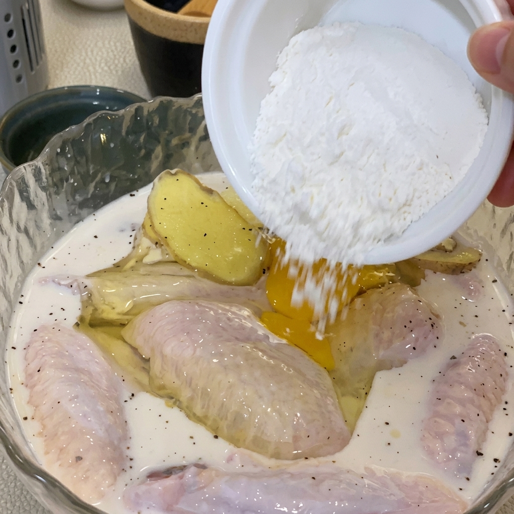 Une main mélangeant un œuf et de la farine dans le bol de poulet.