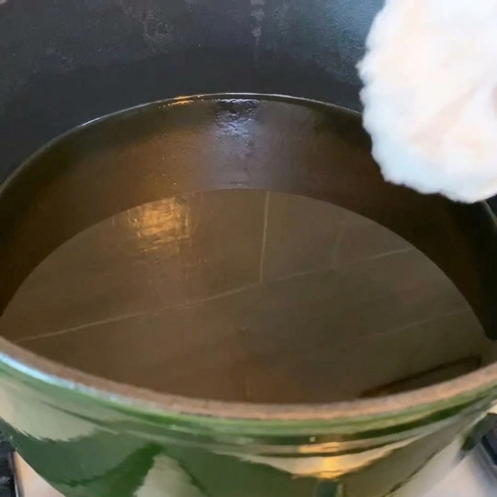 Ailes de poulet en train de frire dans une poêle remplie dhuile chaude.