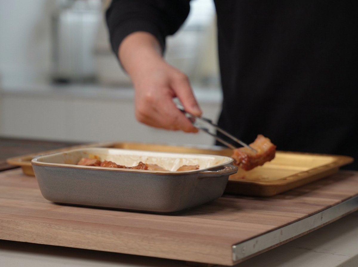 Travers de porc marinés espacés uniformément sur une plaque de cuisson métallique.