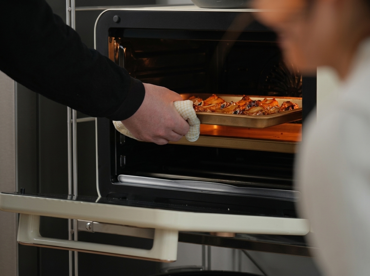 Pince retournant des morceaux de travers de porc rôtis sur une plaque de cuisson.