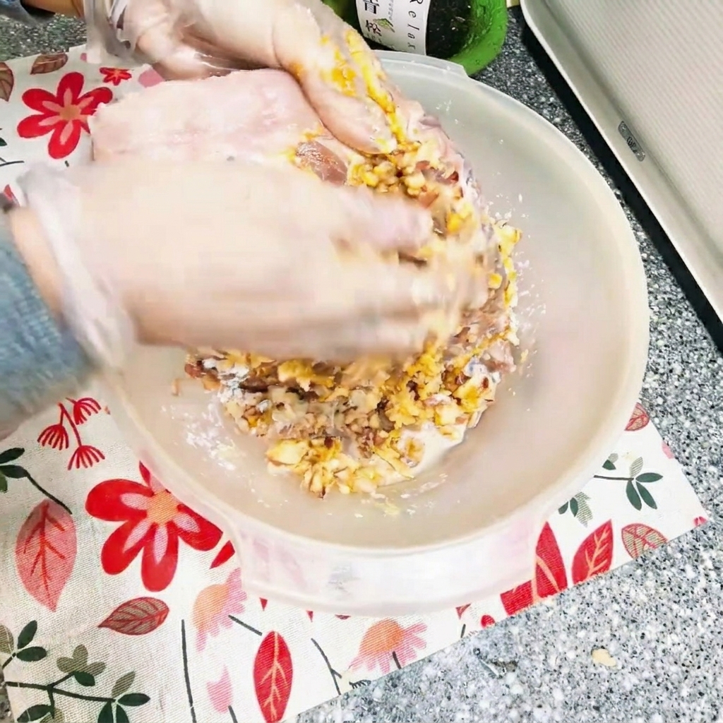 Mains massant un mélange de marinade épaisse sur des travers de porc crus dans un bol.