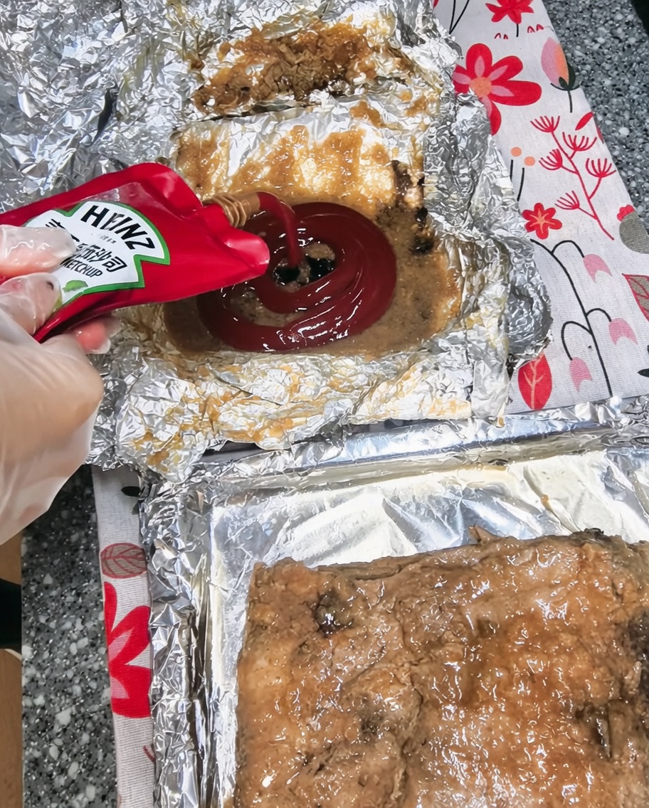 Ketchup versé dans un bol contenant les jus de cuisson et dautres ingrédients de la sauce.