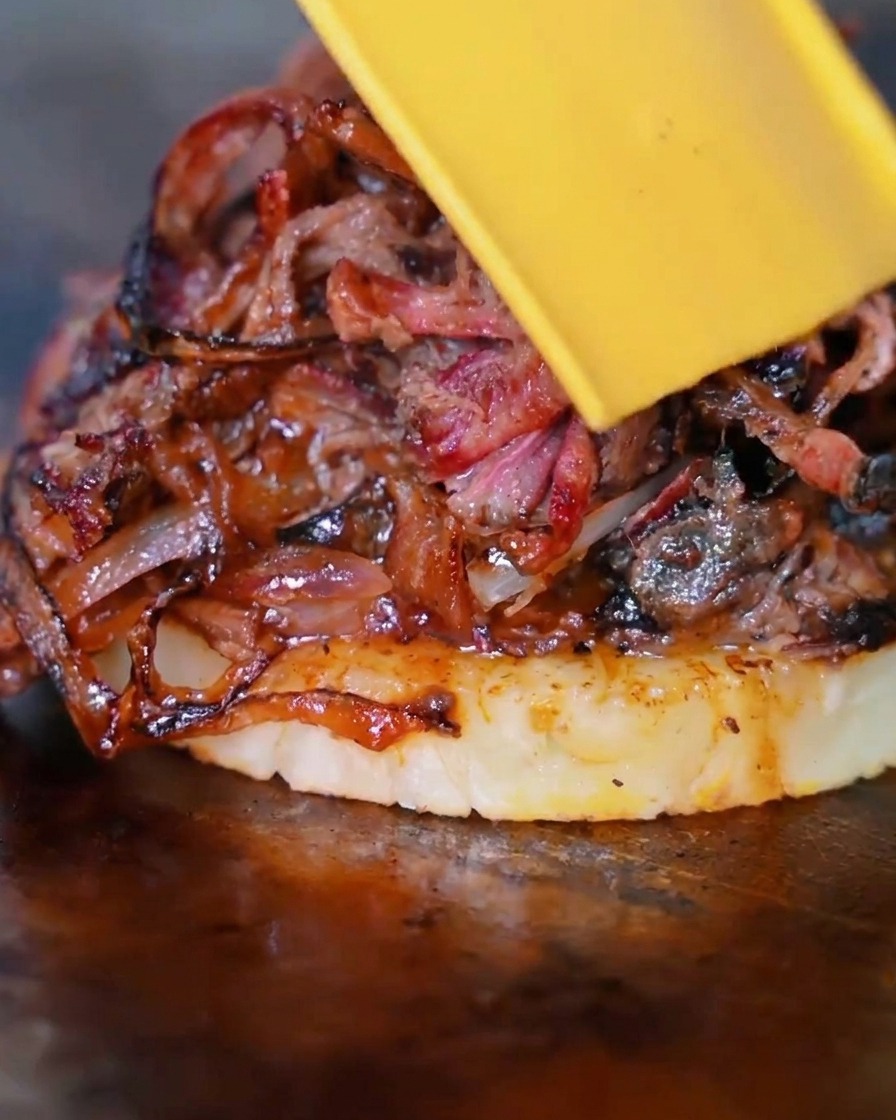 Une tranche de fromage jaune fondant sur le mélange bœuf, oignons et ananas.