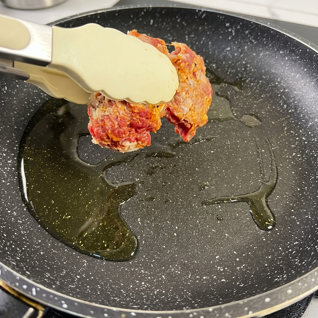 Morceaux de brisket assaisonnés saisissant dans une poêle chaude avec de lhuile, prenant une couleur brun foncé.