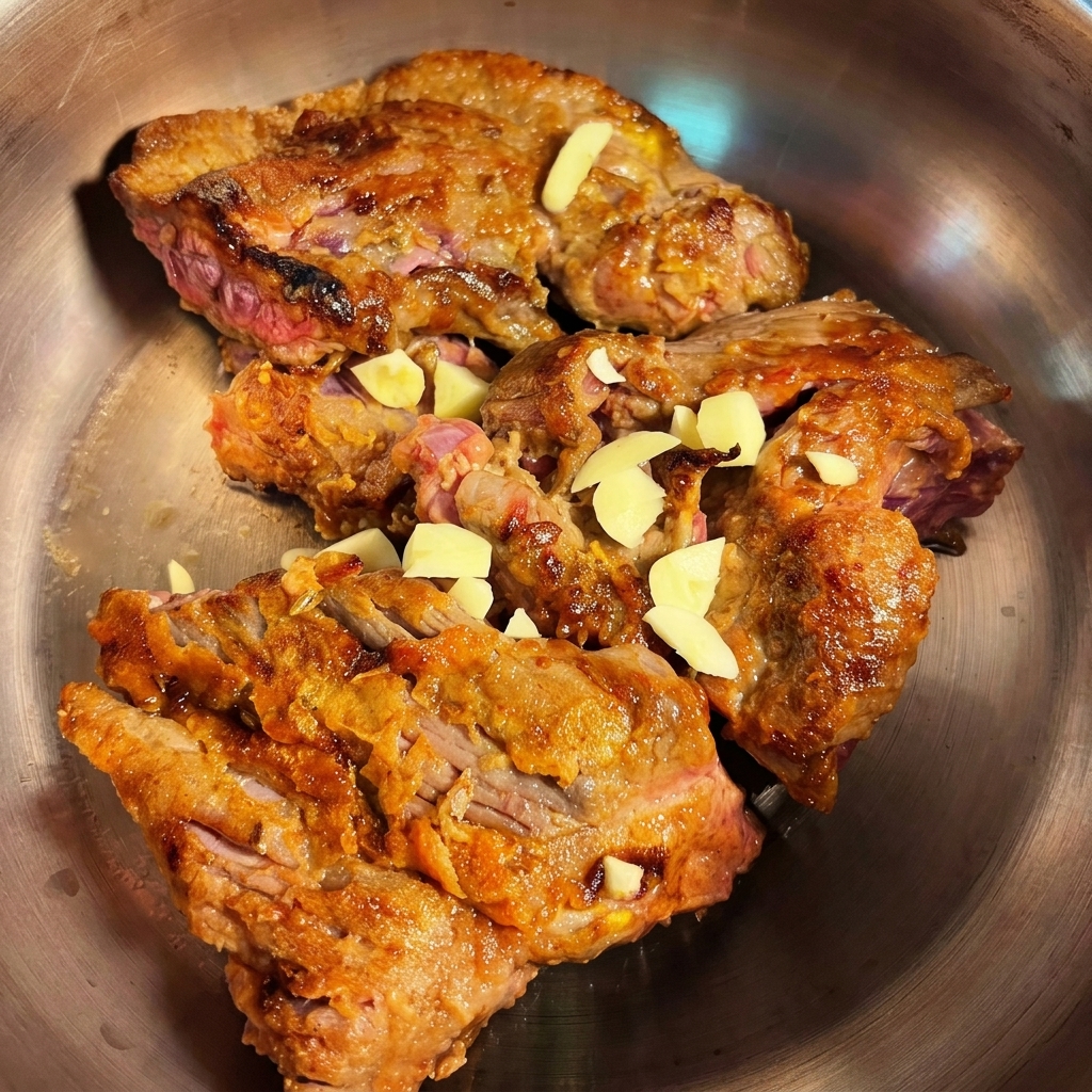 Morceaux de brisket saisis ajoutés dans un autocuiseur avec de lail et des oignons hachés prêts à cuire.