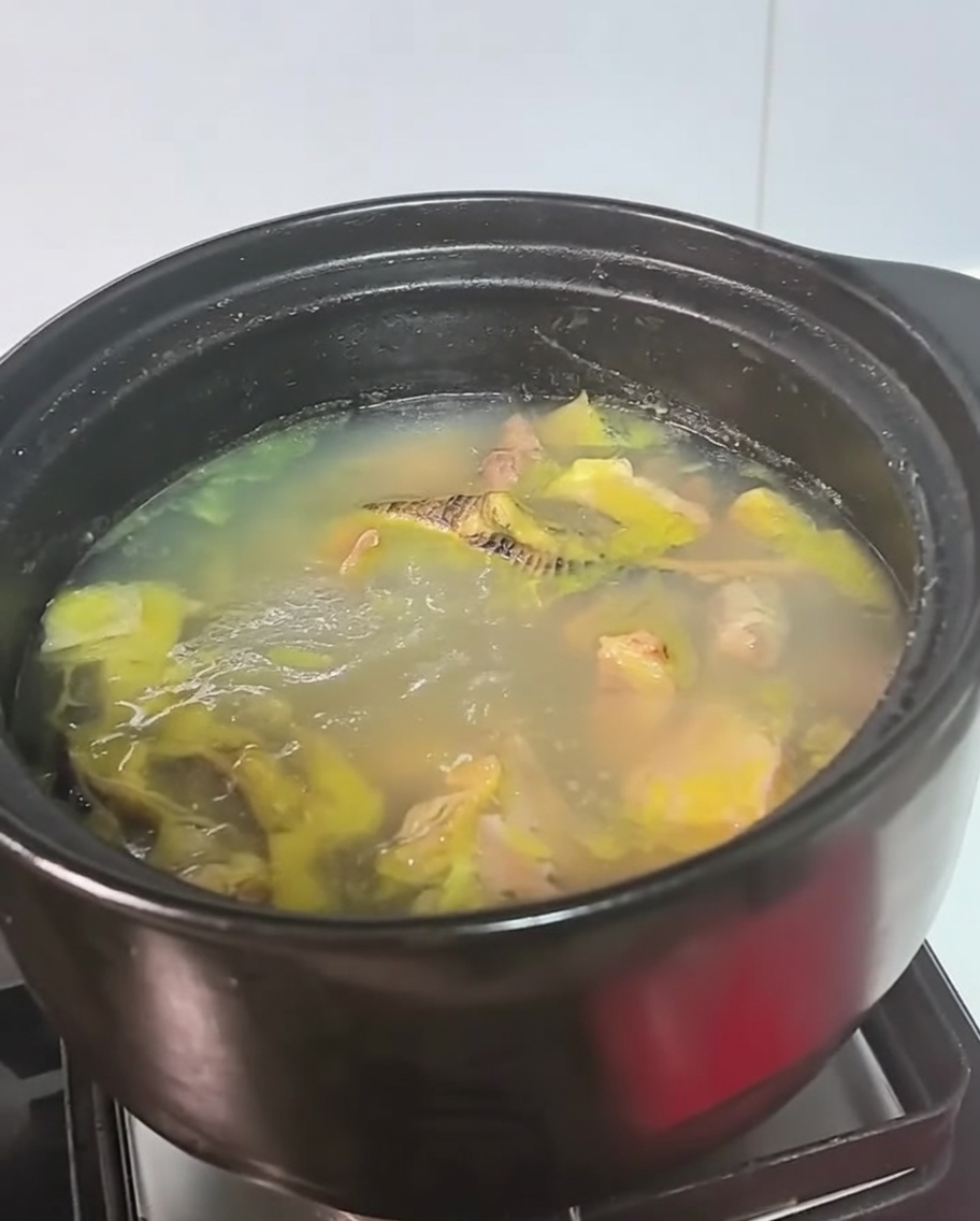 Une casserole noire de soupe au poulet qui mijote sur un feu.
