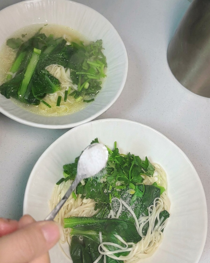 De la soupe au poulet chaude versée à la louche dans un bol de nouilles.