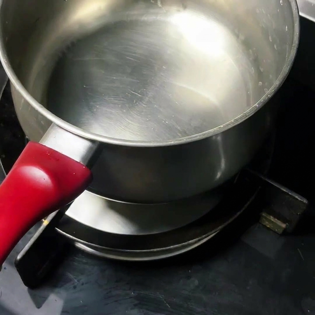 Un œuf cru qui cuit dans une casserole en inox propre sur la cuisinière.
