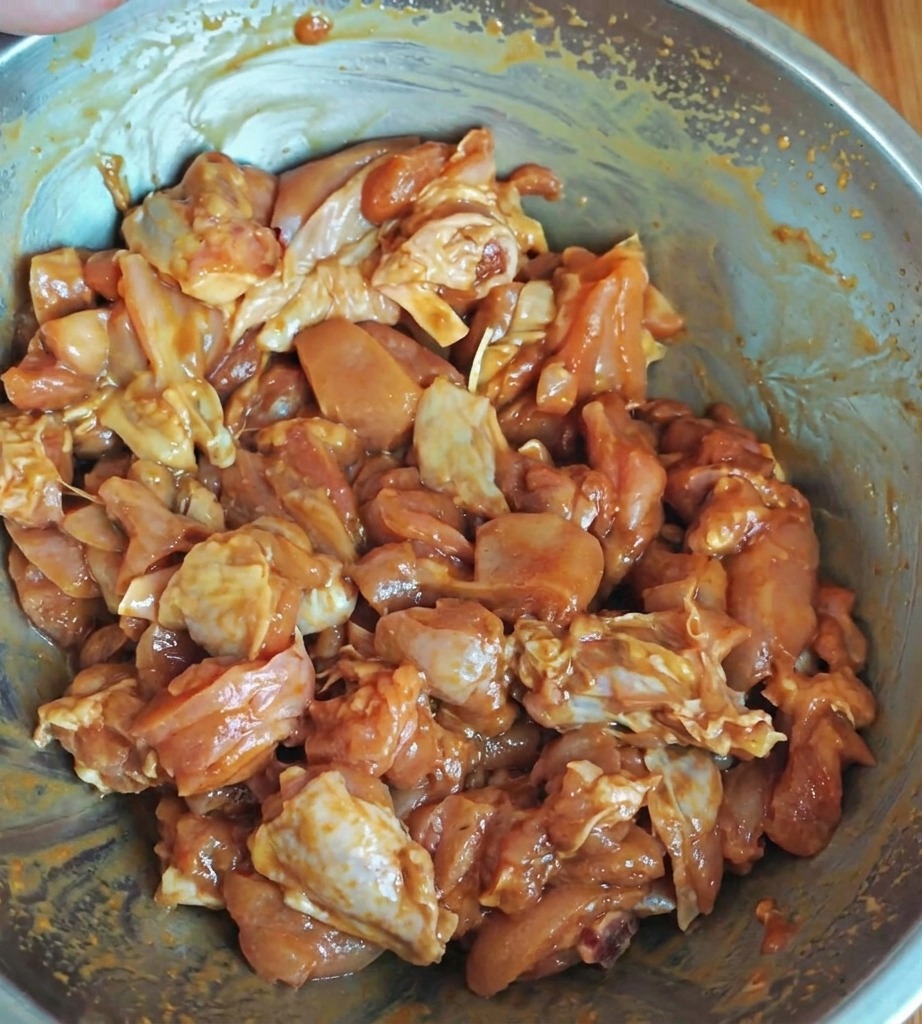Morceaux de poulet marinant dans un bol avec une sauce brillante.