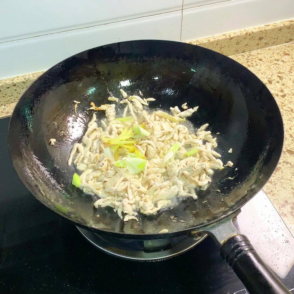 Oignons nouveaux et gingembre sautés avec le poulet dans un wok.