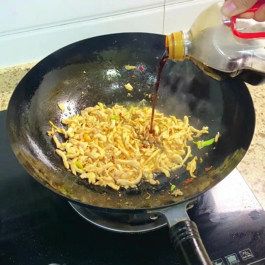 Sauce soja noire versée dans le wok avec le poulet sauté.