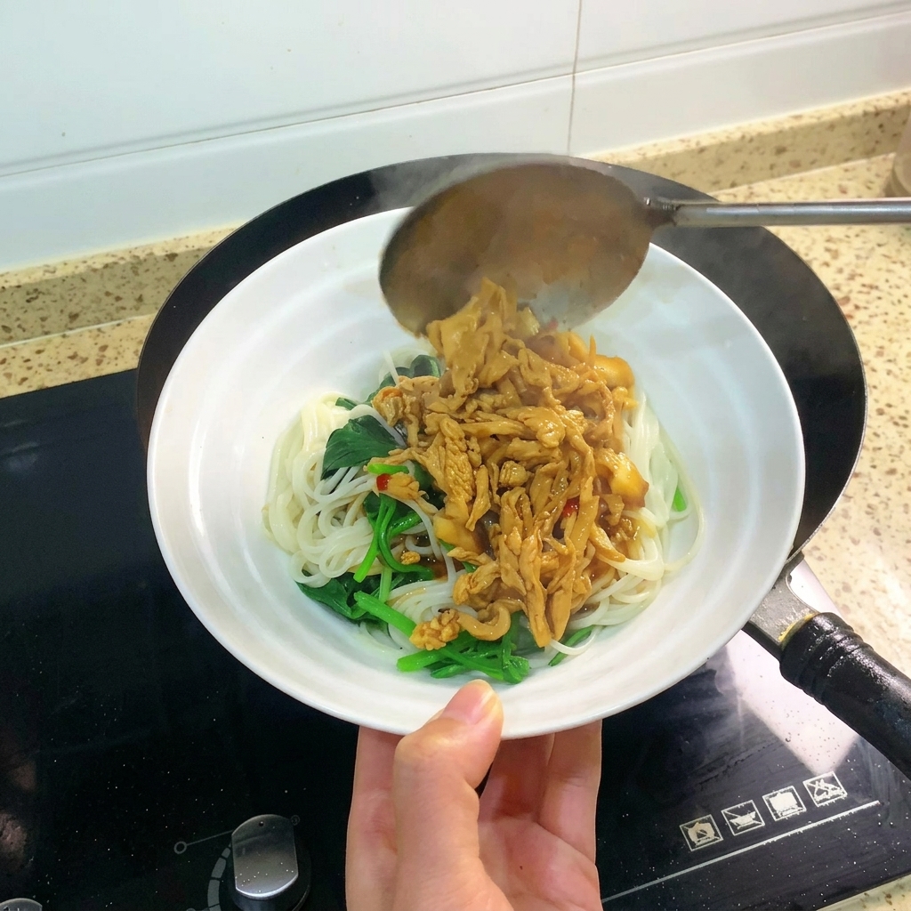 Une louche versant une portion généreuse de poulet braisé et de sauce sur un bol de nouilles.