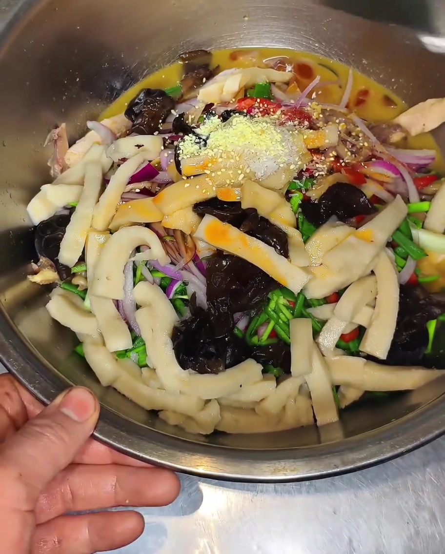 Gros plan dun bol rempli de poulet, de pousses de bambou, de champignons noirs et de poivrons assaisonnés de bouillon de poulet en poudre et de sel.