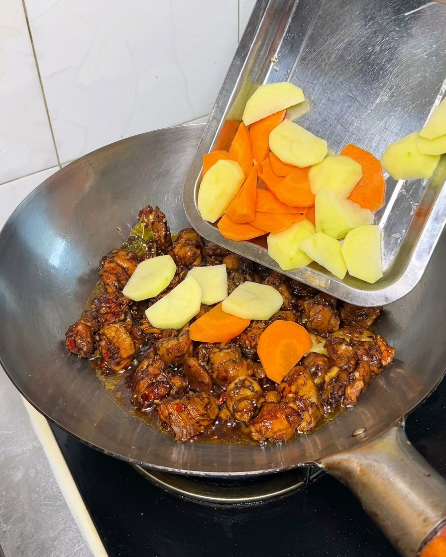 Morceaux de pommes de terre et carottes ajoutés au poulet.