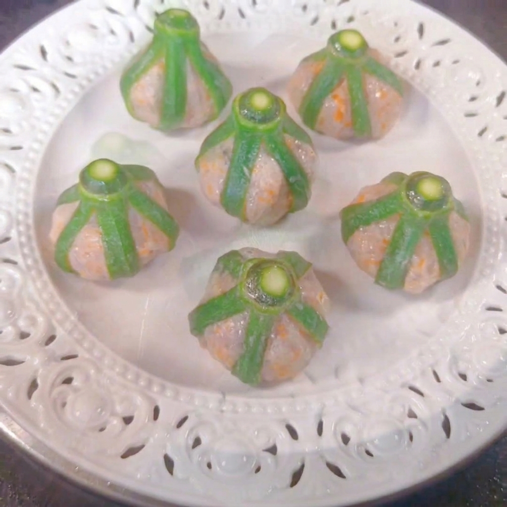 Six bouchées de gombos aux crevettes disposées sur une assiette blanche à lintérieur dun cuiseur vapeur.