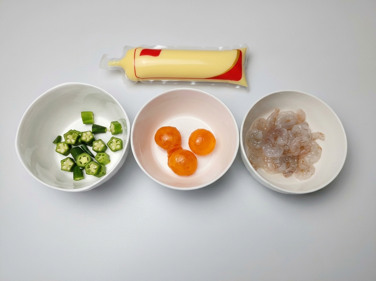 Trois bols blancs contenant des gombos coupés, des jaunes dœufs salés et des crevettes crues, à côté dun tube de tofu aux œufs.