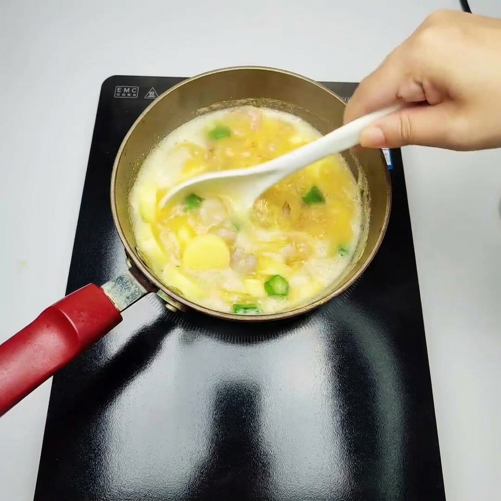 Une louche blanche remuant doucement une soupe jaune frémissante garnie de crevettes cuites, de morceaux de gombos verts et de tranches de tofu aux œufs.