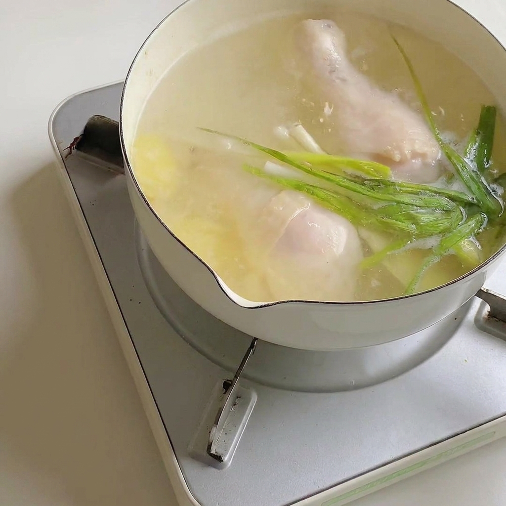 Sachet dassaisonnement pour ramen versé dans la casserole de bouillon avec le poulet.