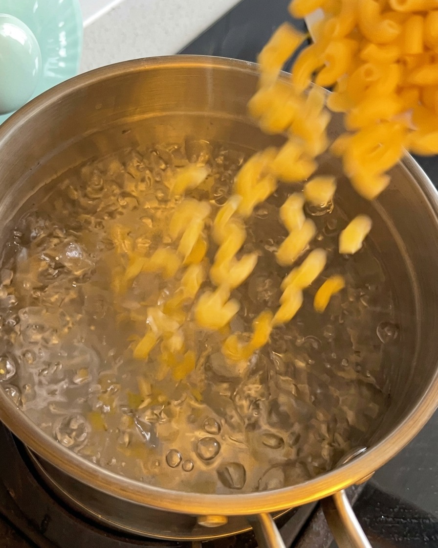 Macaronis secs versés dans une casserole deau bouillante.
