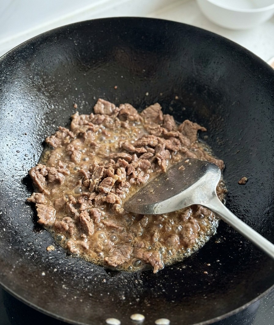 Tomates fraîches coupées en dés ajoutées au bœuf rissolé dans un wok.