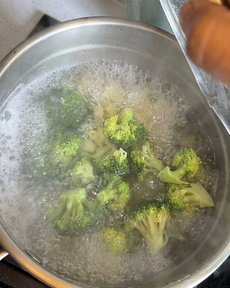 Fleurons de brocoli dun vert éclatant plongés dans leau bouillante avec les macaronis en cuisson.