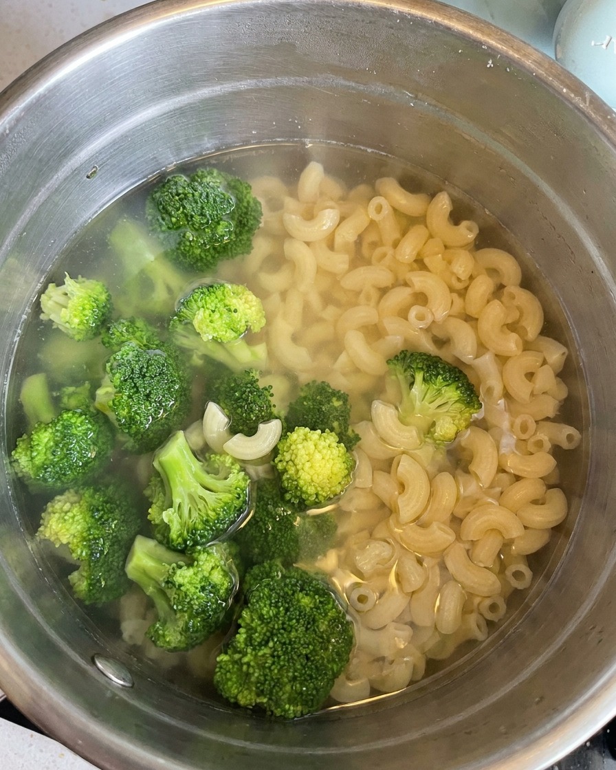 Écumoire retirant les macaronis cuits et les bouquets de brocoli dune casserole deau.
