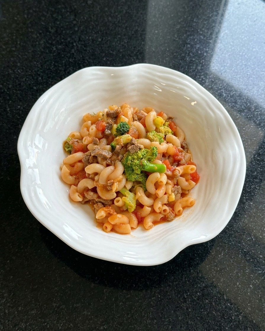 Plat de macaronis terminé, dressé dans un bol blanc et garni dherbes séchées.