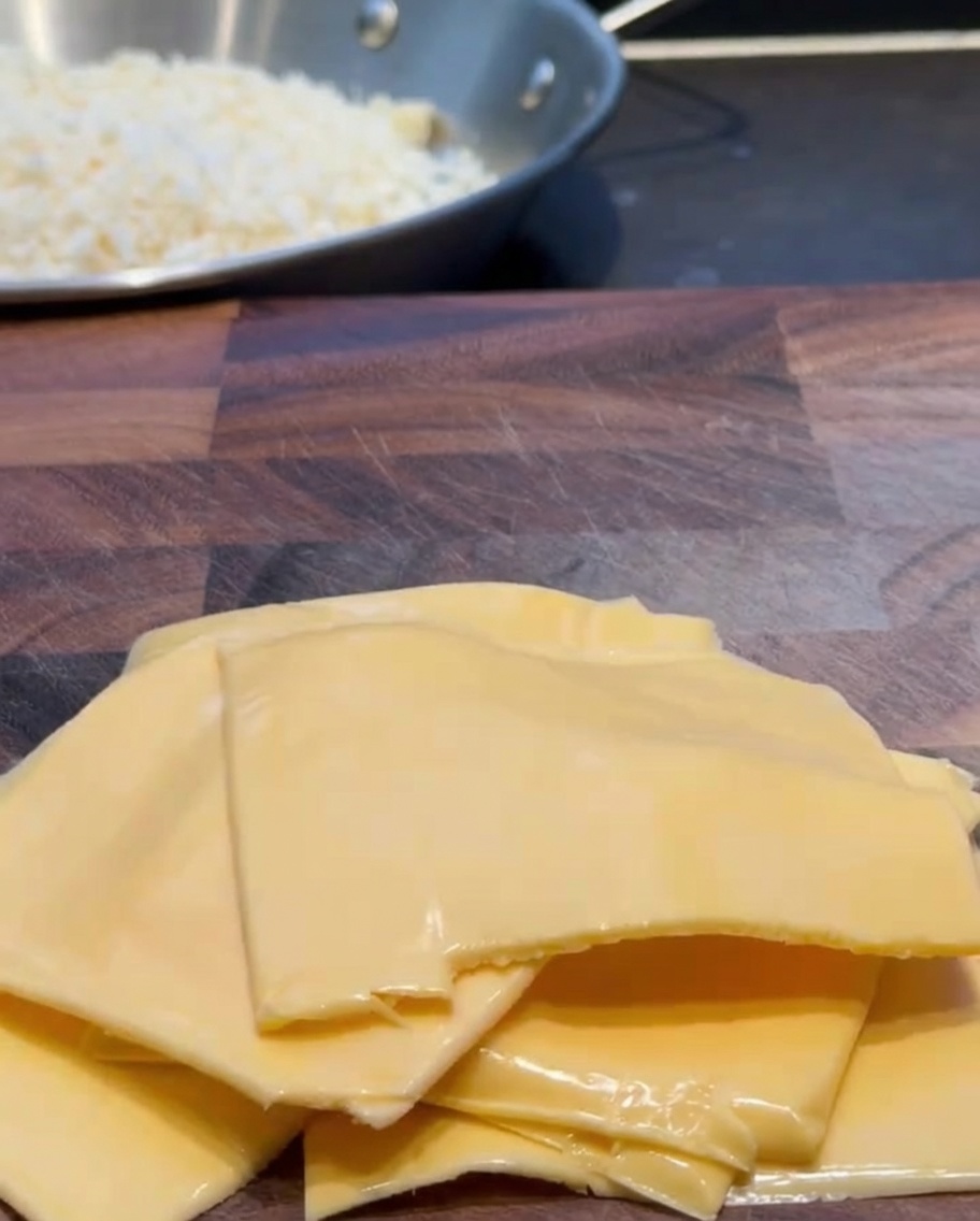 Tranches de cheddar coupées en morceaux sur une planche à découper en bois.