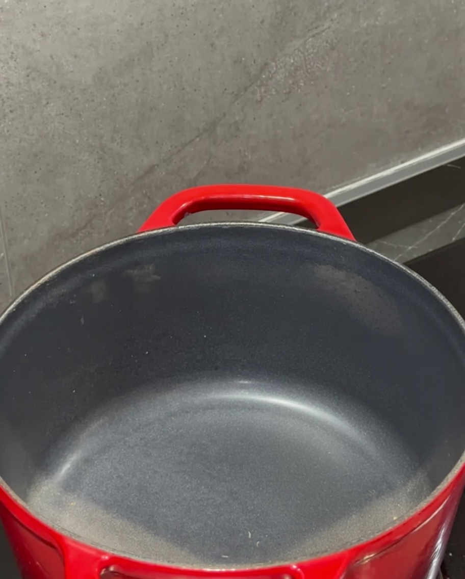 Un bloc de beurre qui fond dans une casserole rouge sur le feu.